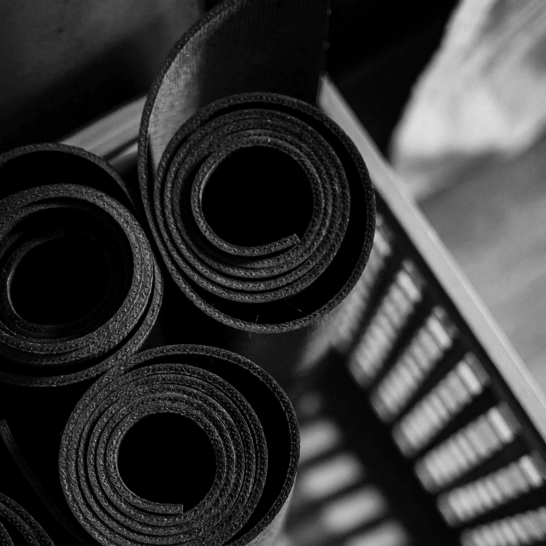 Schwarz-weißes Bild von aufgerollten Yogamatten in einer Holzbox.